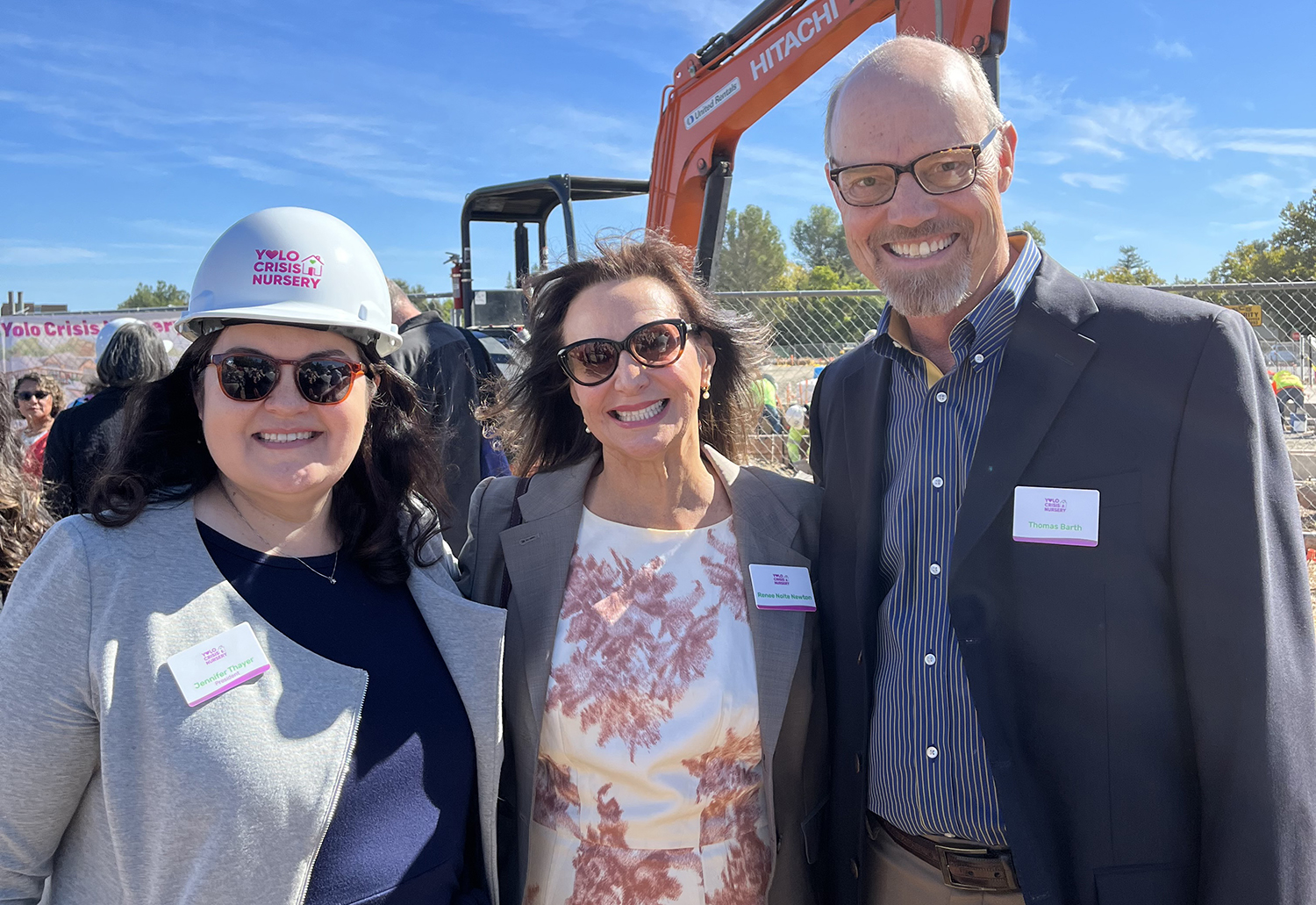Three people standing with a bulldozer in the background