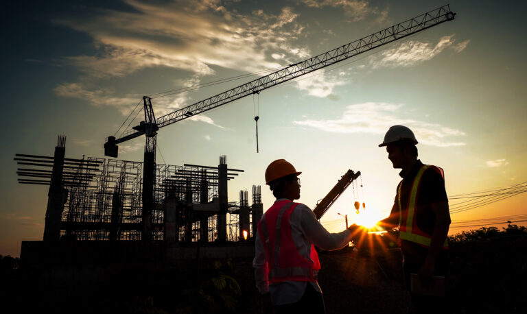 Two people wearing hard hats standing in front of a crane